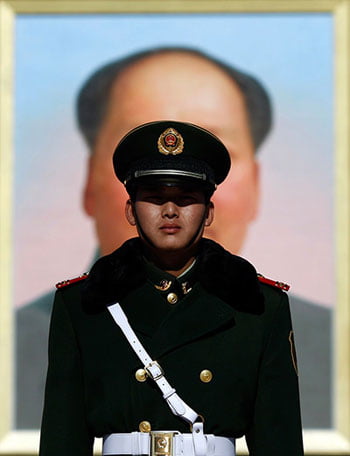 policeman in front of a picture of Mao...